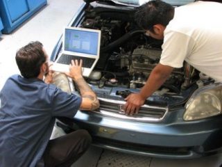 An image of two auto technicians working on a vehicle.