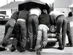 A historical picture of several people working on an old car.